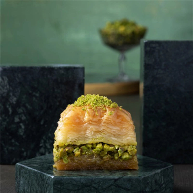 Dry pistachio baklava piece on dark slate